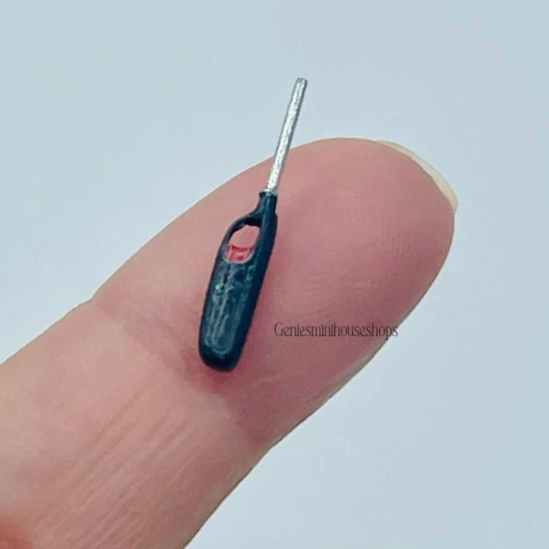 Miniature black lighter on a finger with a white background