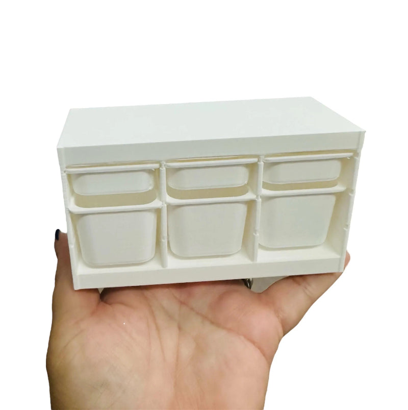 Hand holding a 6-drawer storage bin with multiple small compartments on a white background