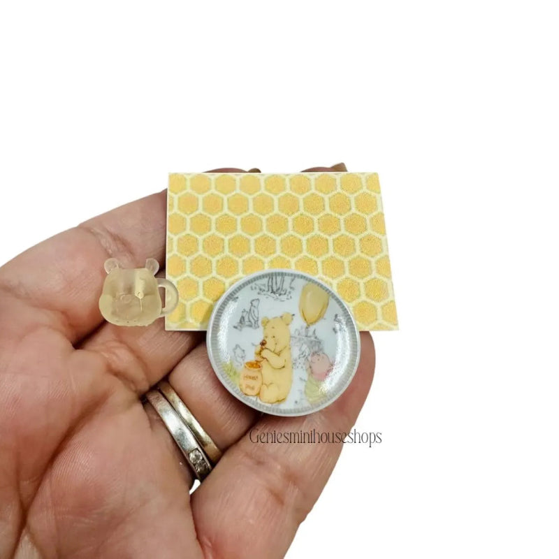 Miniature plate and mug of bear yellow honeycomb background held by a hand.