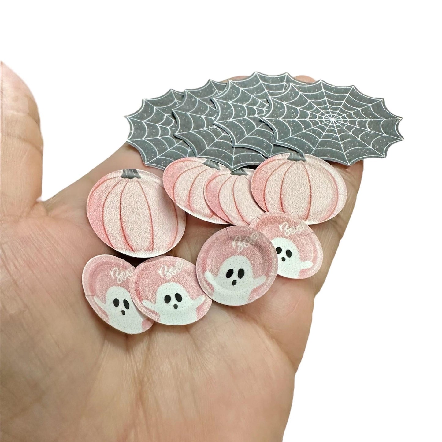 Four decorative plates set with ghost designs held in a hand against a white background