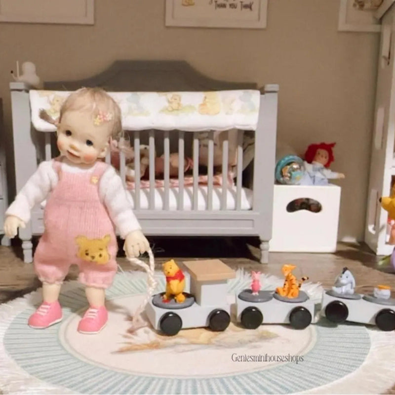 Doll in a pink outfit with a toy train set in a nursery setting