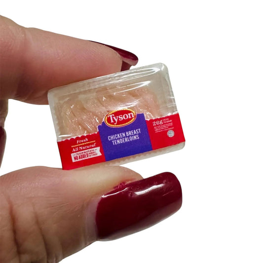 Hand holding a small package of chicken breasts against a white background