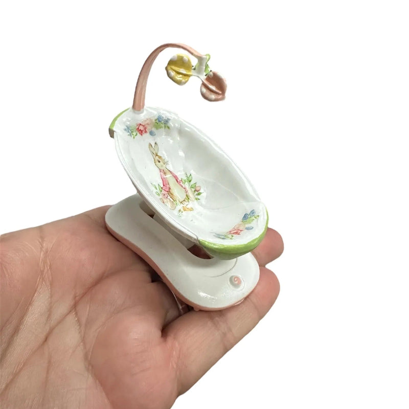 Miniature decorative baby doll swing rabbit print held in hand on a white background