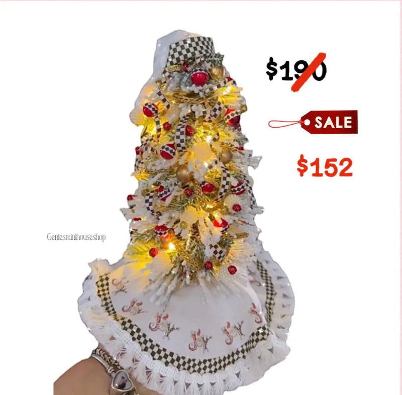 Decorative Christmas tree with lights and ornaments, held by a person, on a white background.