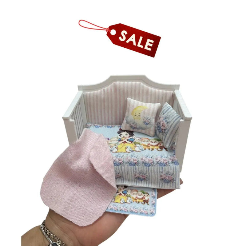 Miniature dollhouse crib with bedding  on a white background