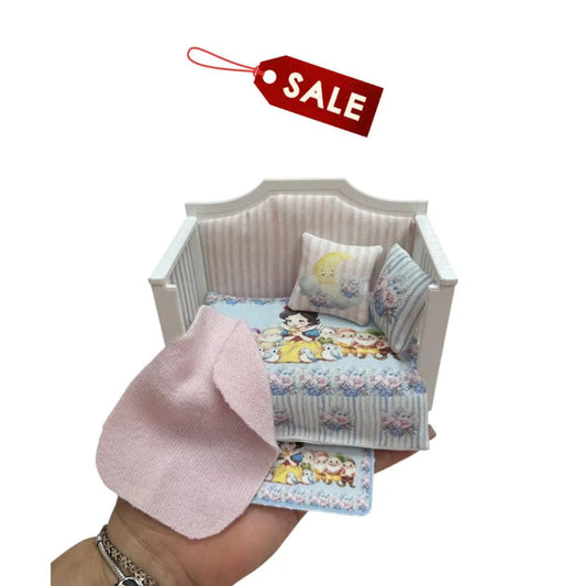 Miniature dollhouse crib with bedding  on a white background