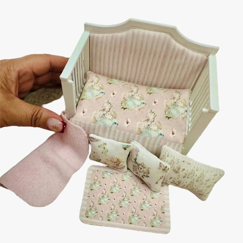 Miniature dollhouse daybed with floral bedding and pillows, held by a hand.