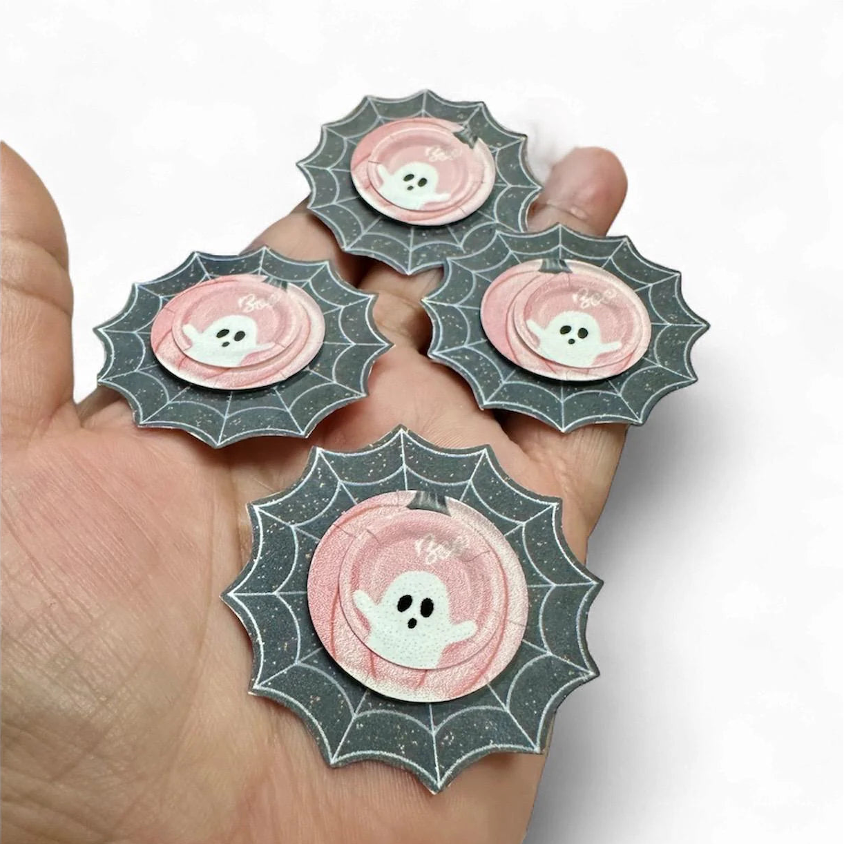 Four decorative plates set with ghost designs held in a hand against a white background