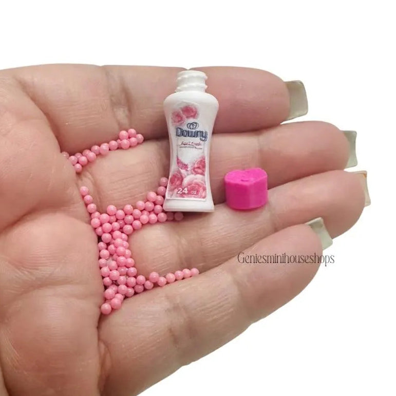 Miniature bottle and pink beads on a hand with a white background