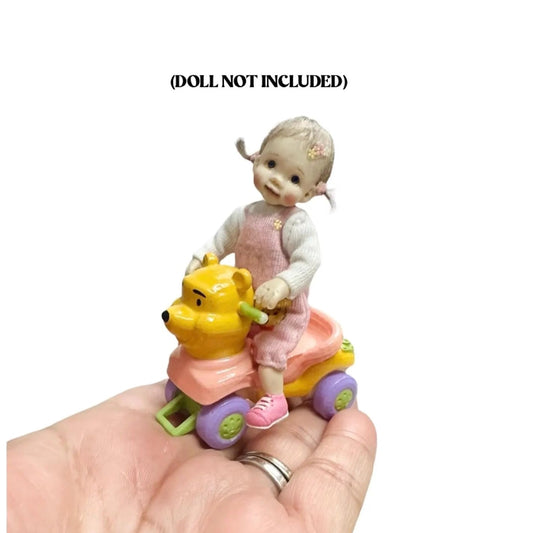 Small toy figure of a doll riding on a ride toy on a white background